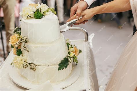 Pareja cortando un elegante pastel de boda de varios pisos en una celebración
