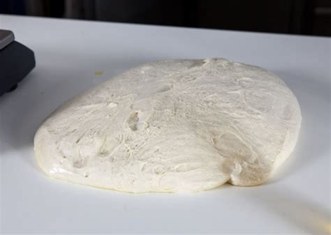 Fotografía de masa madre activa con burbujas y una marca elástica indicando el crecimiento del volumen