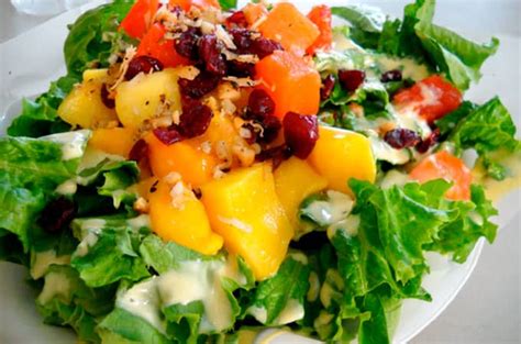 Fotografía de ensalada colorida con lechuga, frutas frescas y nueces en un bol de cristal sobre mesa de madera