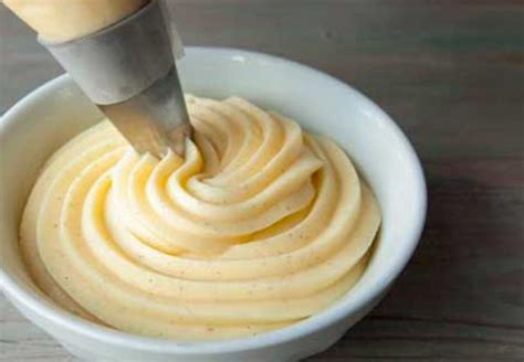 Fotografía de una crema pastelera dorada y espesa en un bol, con una vaina de vainilla al lado