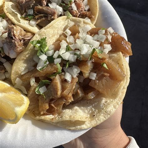 Plato de carnitas y cueritos servidos en tacos con cilantro, cebolla y limón sobre una mesa tradicional mexicana.