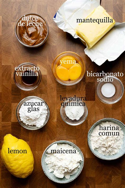Ingredientes para alfajores de maicena dispuestos sobre una mesa de cocina: maicena, harina, azúcar, mantequilla, huevos, ralladura de limón.