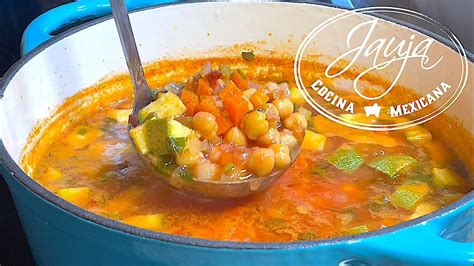 Plato de sopa de garbanzos mexicana humeante servido en un tazón de barro con guarniciones frescas