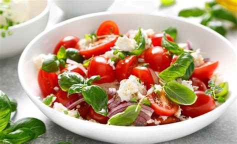 Fotografía cenital de una ensalada de pasta fresca con tomate en dados, albahaca y aceite de oliva