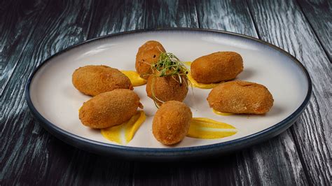 Fotografía de primer plano de croquetas de jibia recién fritas con una textura dorada y crujiente.