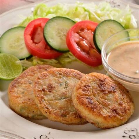 Imagen de tortitas de atún doradas y crujientes servidas en un plato con una guarnición de ensalada fresca.