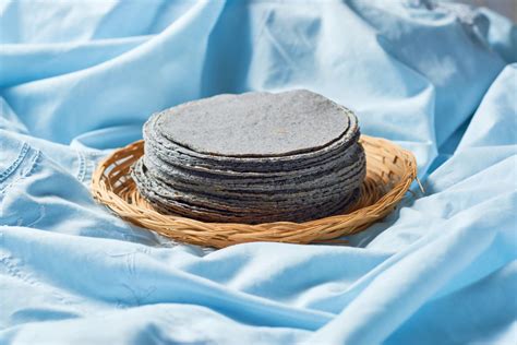 Comparativa visual entre una tortilla de maíz azul auténtica (tonos grisáceos) y una artificial (color intenso artificial).