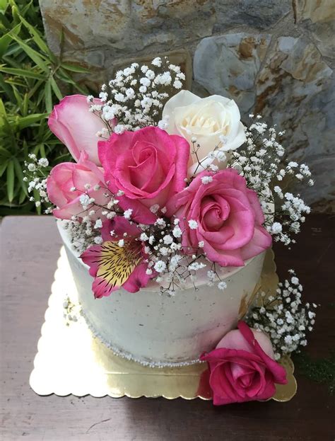 Fotografía profesional de una torta elegante decorada con flores naturales y detalles en fondant para una celebración especial