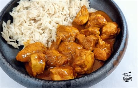Plato de pollo al curry con almendras servido sobre una base de arroz basmati y adornado con cilantro fresco.
