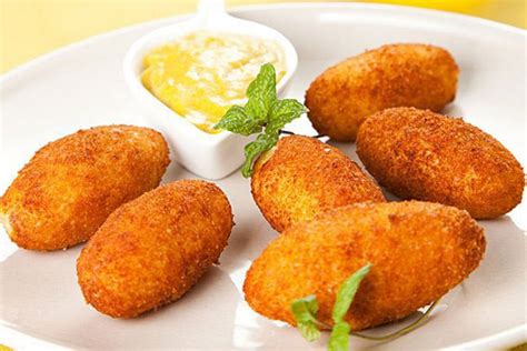 Ilustración de croquetas de pescado doradas y crujientes servidas en un plato con salsa de acompañamiento