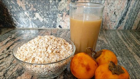 Fotografía de un vaso de colada de avena con naranjilla, decorado con una rodaja de naranja y una ramita de canela.