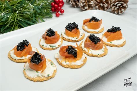 Imagen de una bandeja con diversos canapés de salmón ahumado decorados con eneldo y huevas.