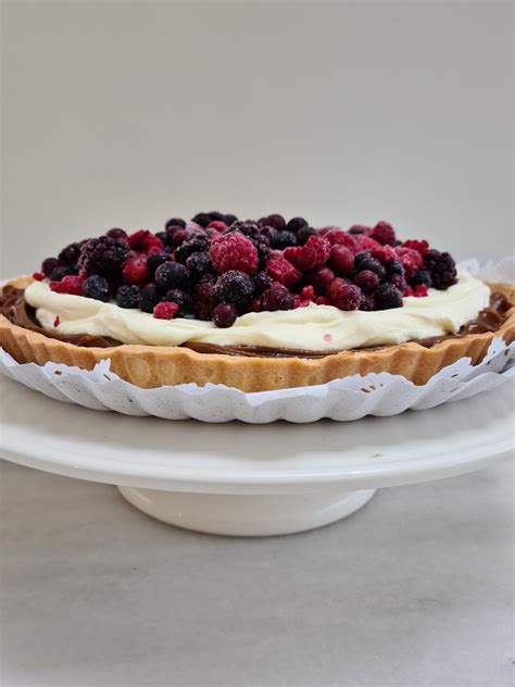Fotografía profesional de una tarta decorada con frutos rojos frescos y una base crujiente