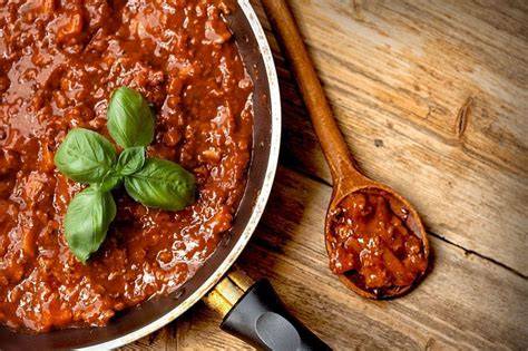 Olla con la salsa boloñesa cocinándose a fuego lento, mostrando la textura y los ingredientes.