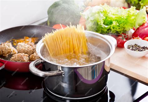 Espaguetis cocinándose en agua hirviendo en una olla grande.