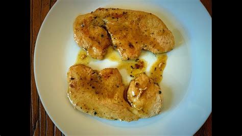 Filetes de pavo dorándose en mantequilla en una sartén amplia, añadiendo güisqui para flambeado.