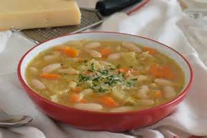 Fotografía apetitosa de un plato de sopa cremosa de alubias con verduras, servida con pan rústico.