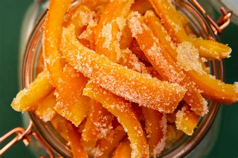 Fotografía profesional de cascaritas de naranja confitadas brillantes y azucaradas dispuestas sobre una rejilla de repostería.