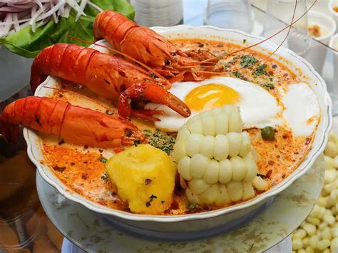Plato de chupe de camarones peruano, decorado con perejil y acompañado de maíz y papas.