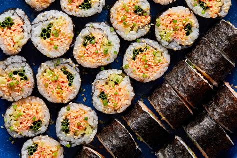Proceso de montaje del rollo de sushi, mostrando la colocación de los ingredientes sobre el arroz y alga nori.
