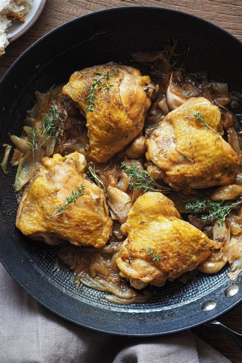 Fotografía gastronómica de un pollo al cava servido en una fuente con hierbas aromáticas frescas.