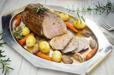 Redondo de ternera asándose en una bandeja de horno con verduras.
