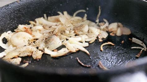 trozos de pollo cocinándose en una sartén con cebolla y ajo