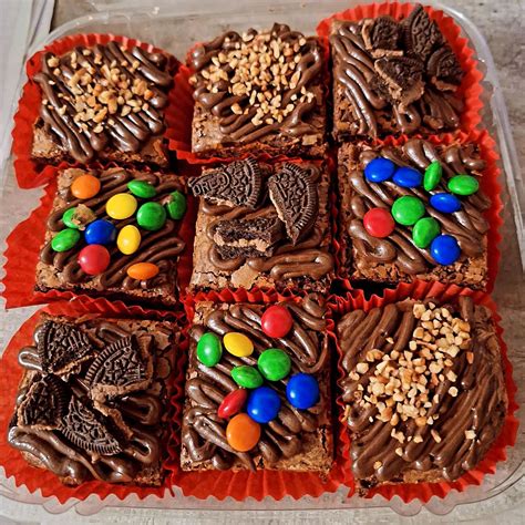 Fotografía de mini brownies individuales recién horneados, decorados con frutos secos y una textura brillante en la superficie.