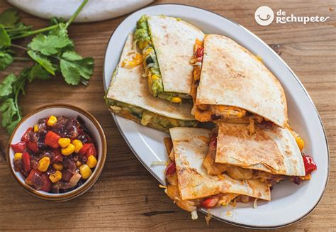 Plato de quesadillas de pollo y aguacate servidas con cilantro y lima.