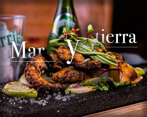 Fotografía de una tabla de carnes y mariscos servida en mesa con vista al mar