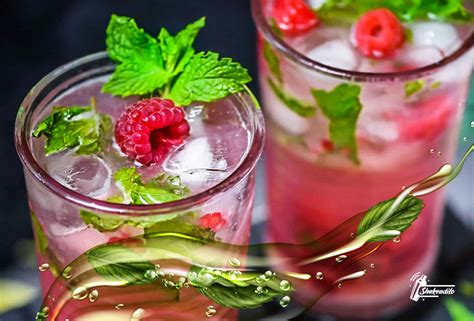 Fotografía profesional de un mojito de frambuesa con guarnición de hierbabuena fresca y frambuesas naturales