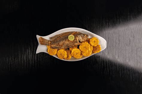 Plato de pescado frito servido con limón y patacones