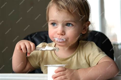 Bebé sonriendo mientras come yogur con una cuchara