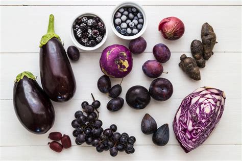 Composición de frutas moradas y púrpuras, como arándanos, uvas moradas y berenjena.