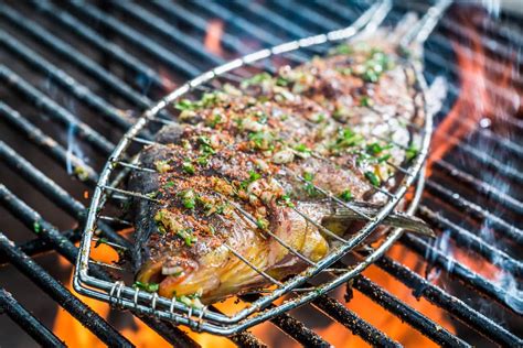 Persona limpiando una parrilla para pescado después de usarla