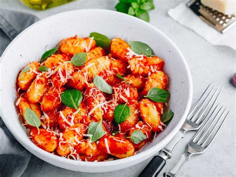Plato de ñoquis servido con salsa de tomate y albahaca