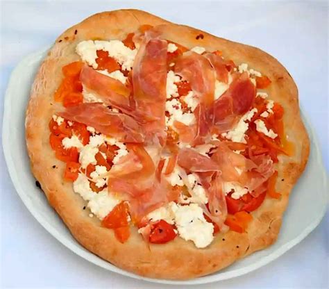 Primer plano de una pizza de jamón serrano recién salida del horno, con el queso fundido y el jamón añadido en el último momento.