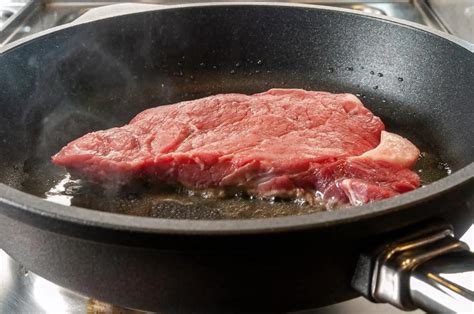 Filete de vacuno sellándose en un sartén antes de ir al horno.