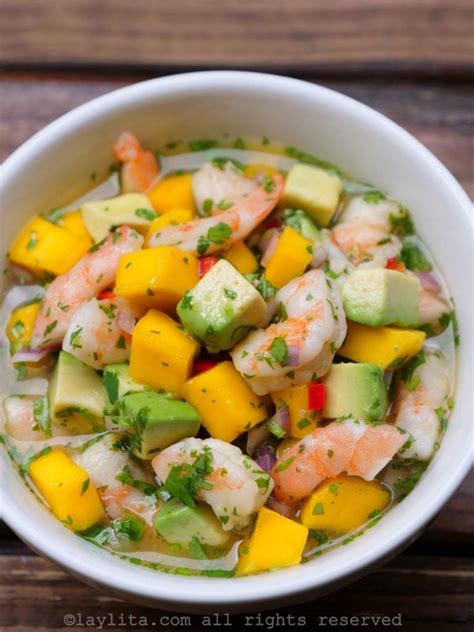 Ceviche de camarones con trozos de mango, aguacate y cebolla morada, servido en un bol.