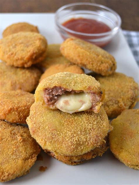 Foto de primer plano de aros de cebolla rellenos cortados por la mitad, mostrando el queso cheddar fundido y la carne jugosa