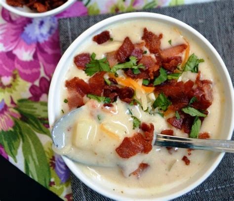 Plato de sopa cremosa de papa servido en un tazón rústico, decorado con trocitos de tocino crujiente, queso cheddar rallado y cebollín fresco.