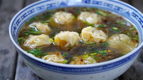 Fotografía gastronómica de un tazón de sopa china tradicional con wonton, cebollín y caldo transparente