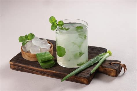 Un vaso decorado con un mocktail tropical de aloe vera, acompañado de rodajas de lima y piña.