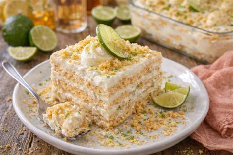 Fotografía de una carlota de limón servida en un plato, mostrando sus capas características de galleta y crema con rodajas de limón decorativas.
