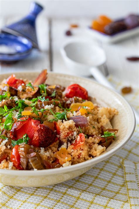 Imagen cenital de una ensalada de cuscús con atún, tomates cherry, aceitunas y verduras frescas servida en un bol elegante.