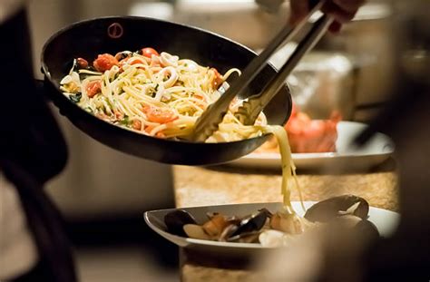 Imagen de un chef italiano salteando pasta en una sartén