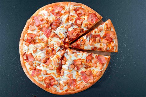 Fotografía de una pizza deluxe de pollo y tocino, con ingredientes frescos y queso derretido, lista para ser servida.