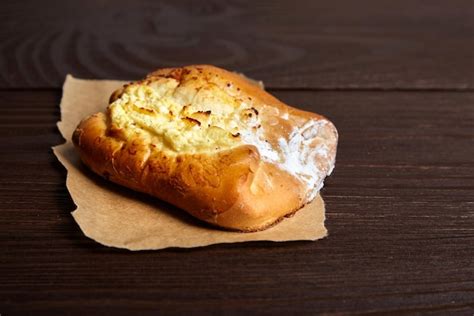 Primer plano de un bollo siendo rellenado con queso crema.