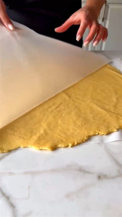 Masa de tarta siendo estirada entre dos papeles de hornear