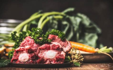 Ingredientes frescos para caldo de carne: huesos, carne, verduras y hierbas aromáticas.